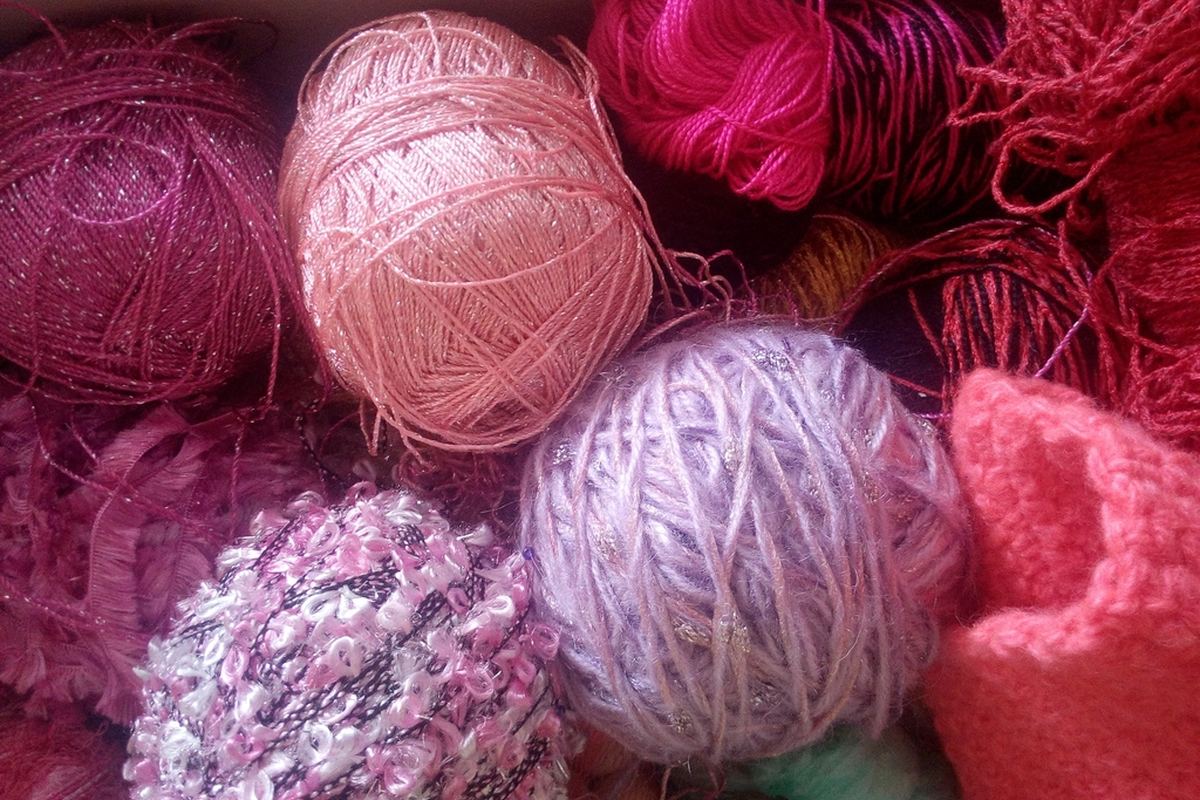 Varios ovillos de algodón de distintos colores apilados en una cesta