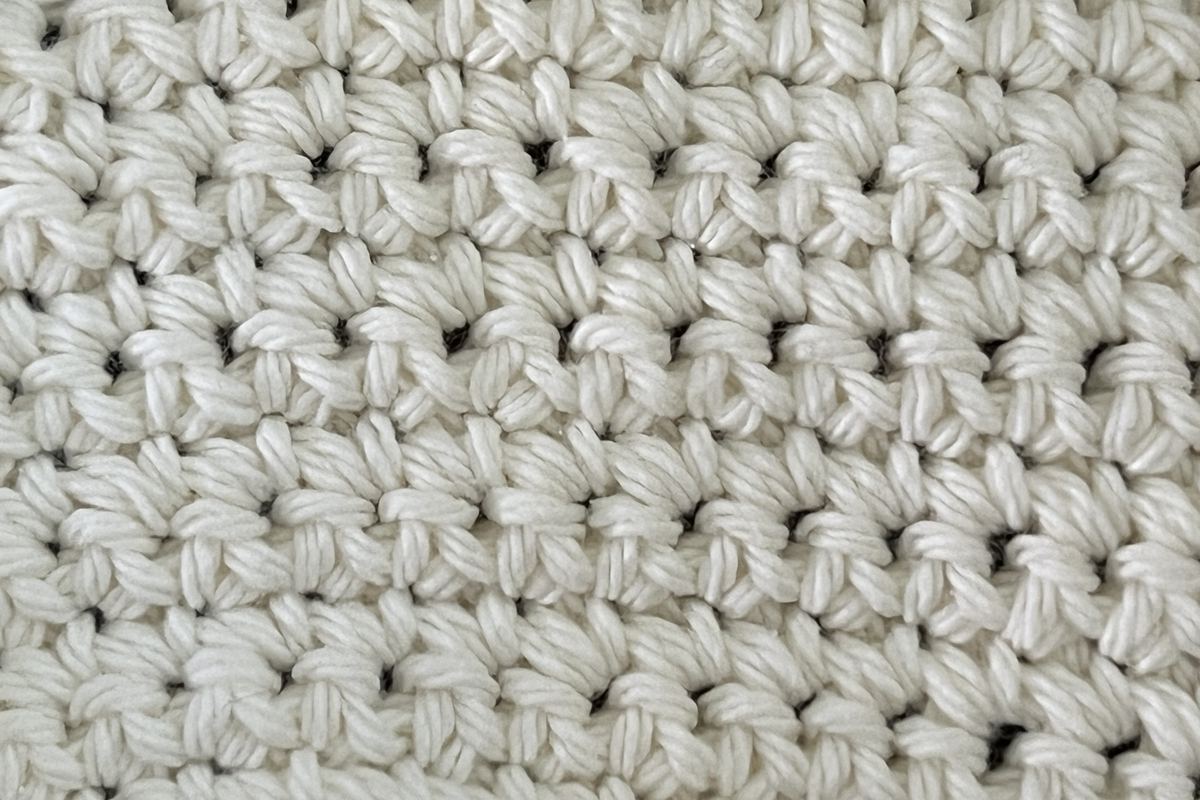 Primer plano de un tejido de crochet en hilo crudo y grueso, con las vueltas de puntos bien definidas y los puntos contables uno a uno